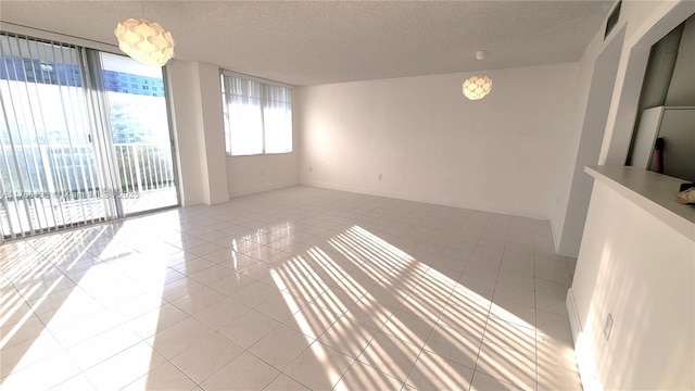 unfurnished room with light tile patterned floors, baseboards, visible vents, and a textured ceiling