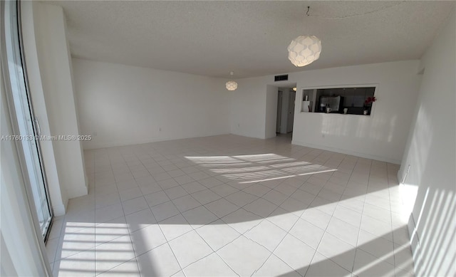 empty room featuring light tile patterned floors, visible vents, and a textured ceiling