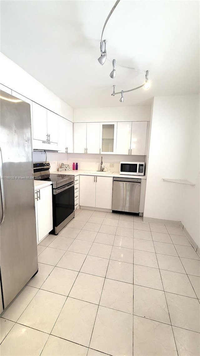 kitchen with light tile patterned floors, a sink, light countertops, appliances with stainless steel finishes, and white cabinetry