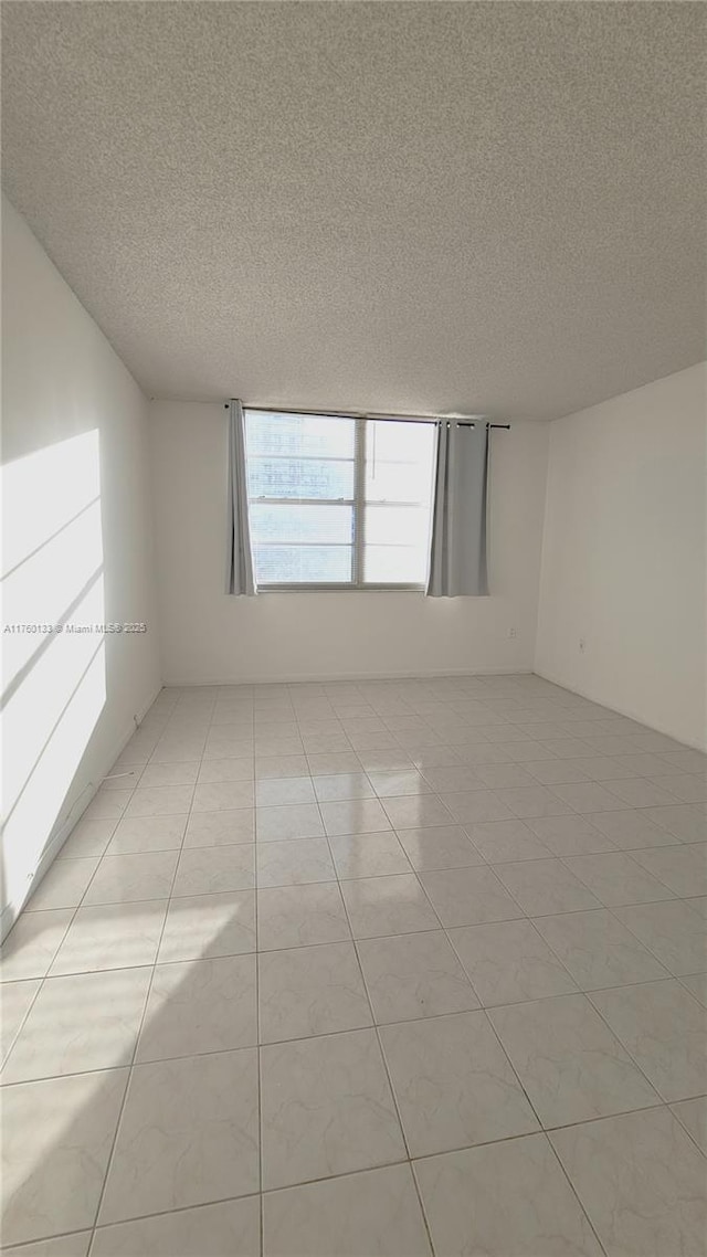 spare room featuring light tile patterned floors and a textured ceiling