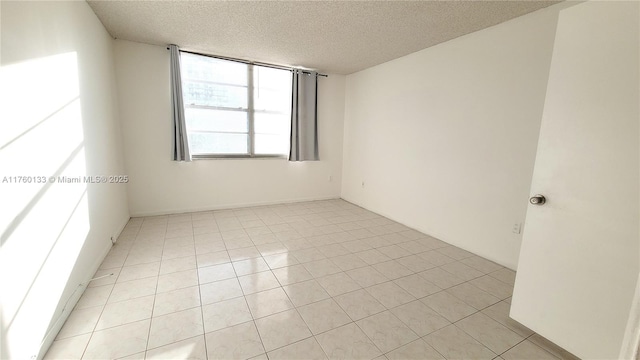 empty room with light tile patterned floors and a textured ceiling