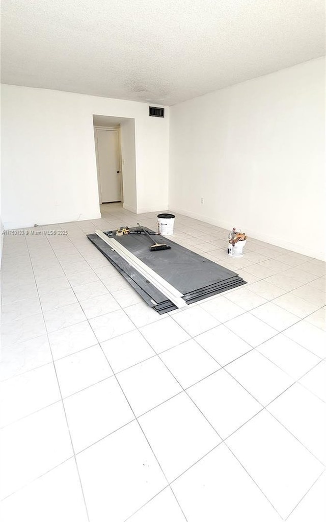 workout room featuring visible vents, a textured ceiling, and light tile patterned flooring