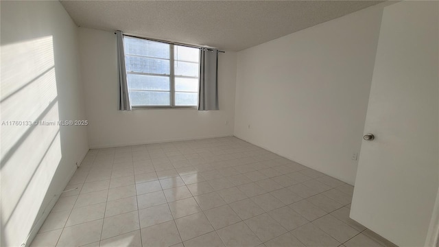 unfurnished room with light tile patterned floors and a textured ceiling