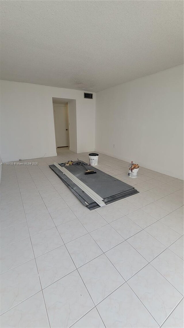 interior space featuring light tile patterned floors, visible vents, and a textured ceiling