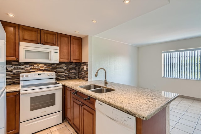 kitchen with brown cabinets, a sink, white appliances, a peninsula, and light tile patterned floors