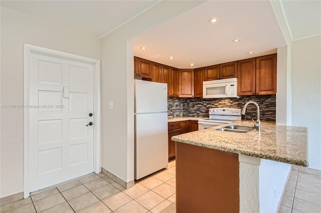 kitchen with a sink, backsplash, white appliances, a peninsula, and light stone countertops