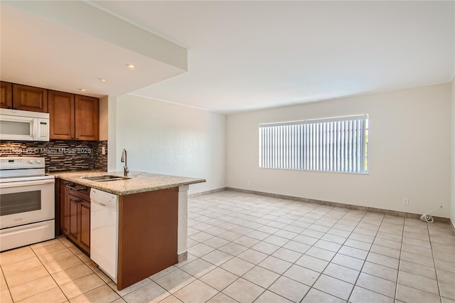 kitchen featuring light tile patterned floors, decorative backsplash, a peninsula, white appliances, and a sink