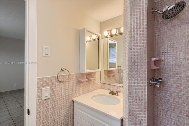 bathroom featuring a wainscoted wall, a tile shower, tile walls, tile patterned flooring, and vanity