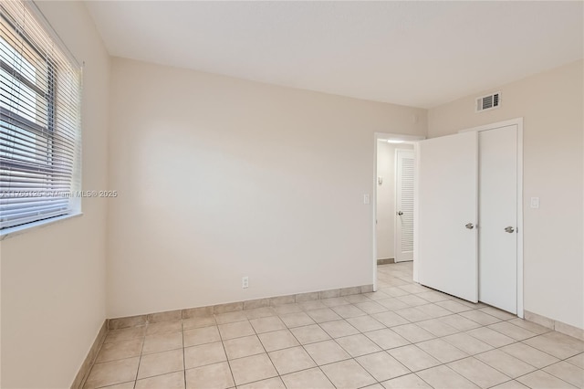 unfurnished bedroom featuring light tile patterned floors, baseboards, and visible vents