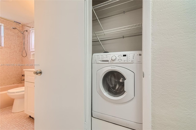 laundry area featuring tile patterned flooring, washer / dryer, a textured wall, and laundry area