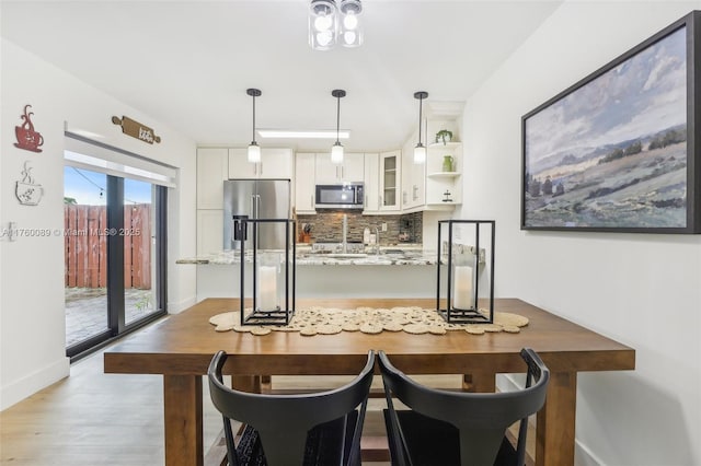 kitchen featuring tasteful backsplash, glass insert cabinets, light stone countertops, appliances with stainless steel finishes, and white cabinets