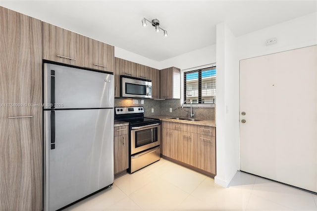 kitchen featuring light stone countertops, a sink, appliances with stainless steel finishes, modern cabinets, and backsplash