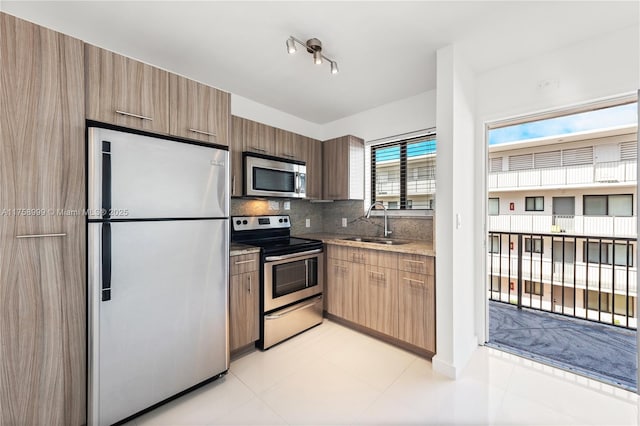 kitchen with decorative backsplash, appliances with stainless steel finishes, modern cabinets, and a sink