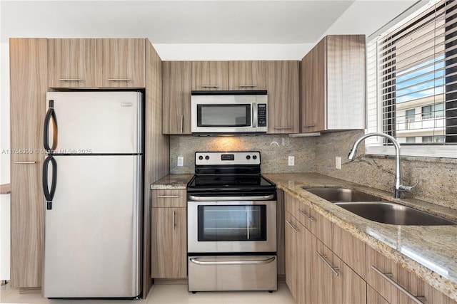 kitchen with tasteful backsplash, light stone countertops, appliances with stainless steel finishes, modern cabinets, and a sink