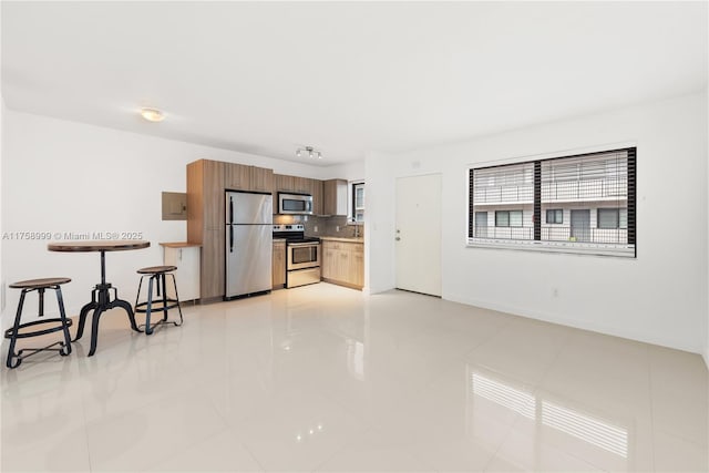 kitchen featuring tasteful backsplash, baseboards, light countertops, light tile patterned floors, and stainless steel appliances