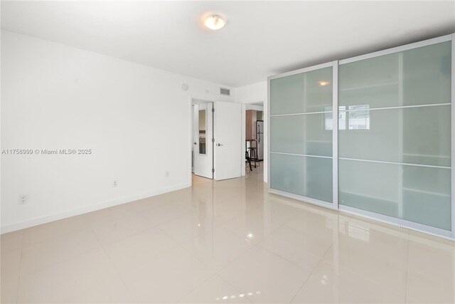 tiled spare room featuring visible vents and baseboards