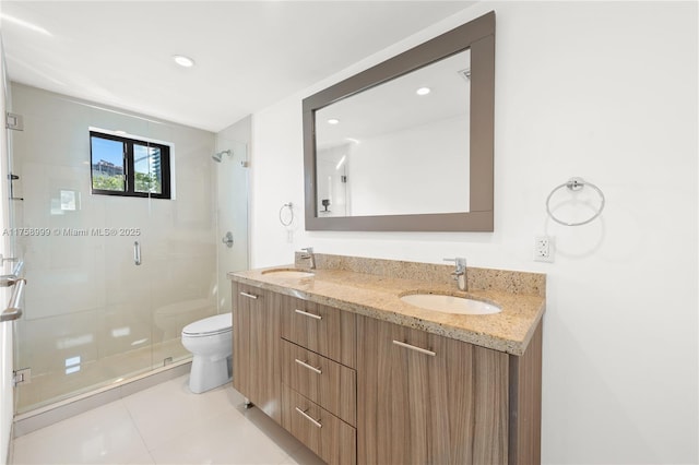 bathroom featuring a shower stall, toilet, double vanity, and a sink