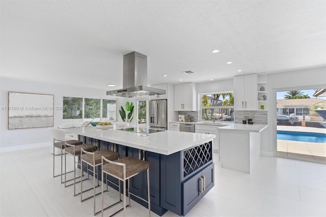 kitchen featuring decorative backsplash, stainless steel appliances, light countertops, and island range hood