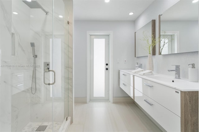 full bathroom with a sink, a marble finish shower, recessed lighting, and double vanity