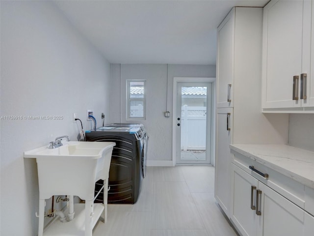 washroom with baseboards, cabinet space, and washing machine and clothes dryer