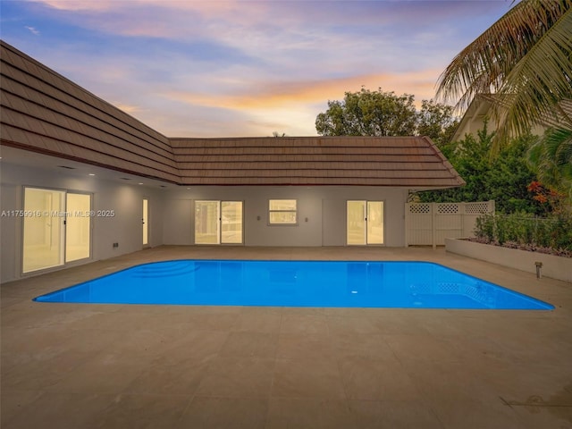 pool at dusk featuring a patio, fence, and a fenced in pool