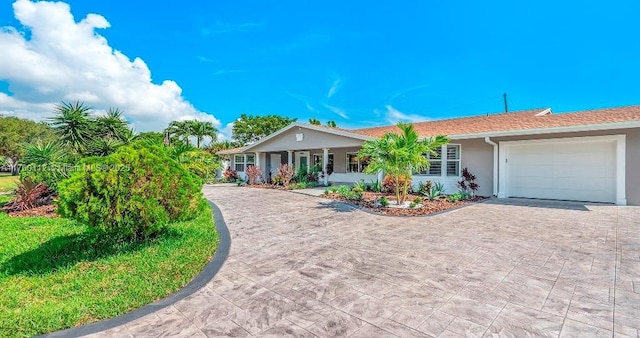 single story home with decorative driveway, a garage, and stucco siding