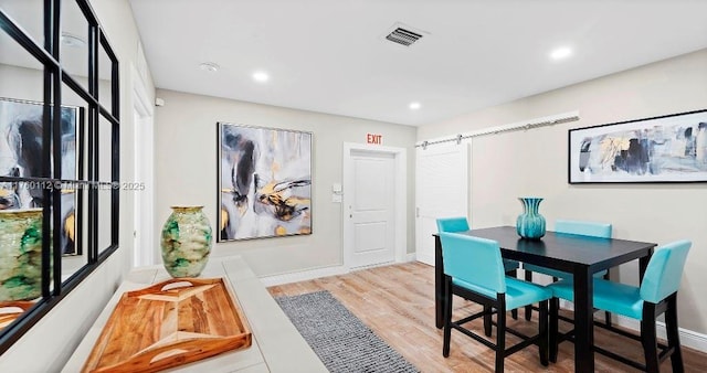 dining space featuring light wood finished floors, visible vents, baseboards, a barn door, and recessed lighting