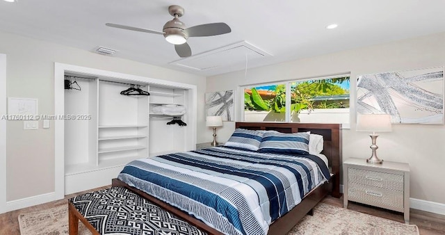 bedroom featuring a ceiling fan, wood finished floors, visible vents, baseboards, and attic access