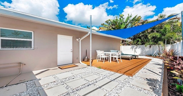 rear view of property with outdoor dining area, a wooden deck, stucco siding, and fence