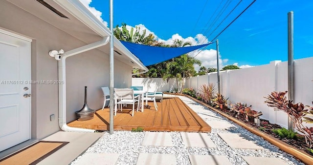 view of patio with outdoor dining area, a wooden deck, and a fenced backyard