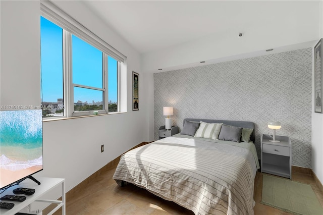 bedroom with tile patterned floors, baseboards, an accent wall, and wallpapered walls