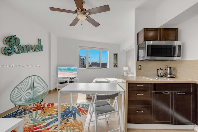 kitchen with ceiling fan, decorative backsplash, light countertops, dark brown cabinetry, and stainless steel microwave