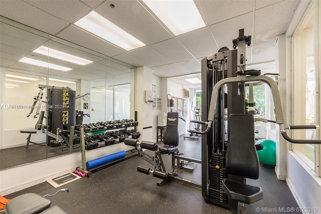 gym featuring a drop ceiling and baseboards