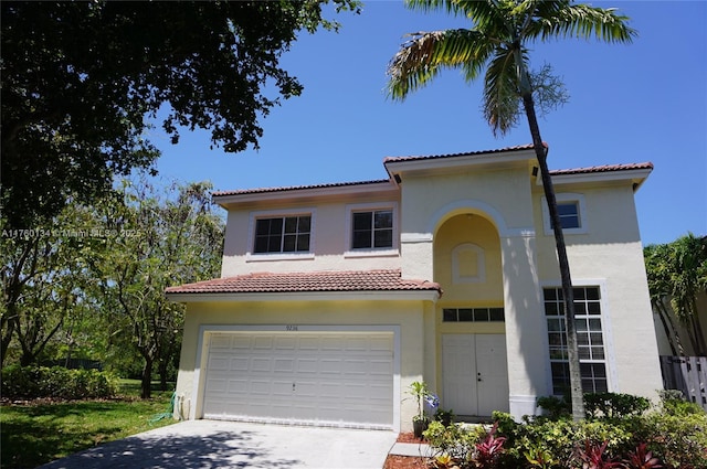 mediterranean / spanish house featuring a tiled roof, an attached garage, driveway, and stucco siding