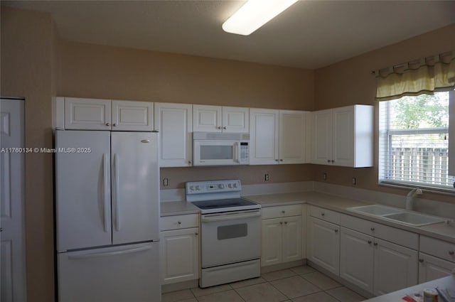 kitchen with white appliances, white cabinets, light countertops, and a sink