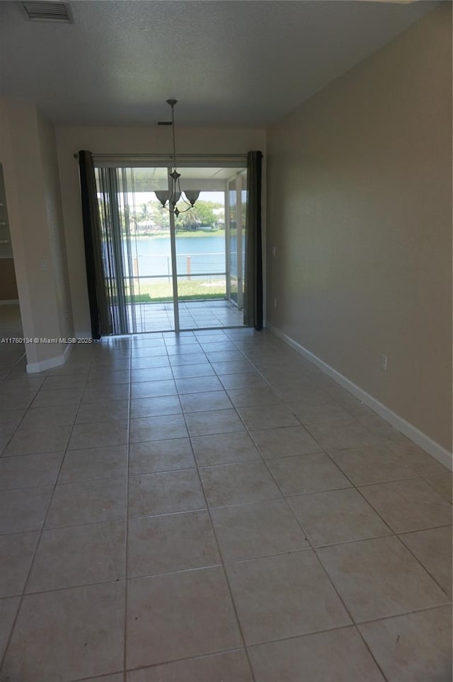 empty room with light tile patterned floors, baseboards, and a textured ceiling