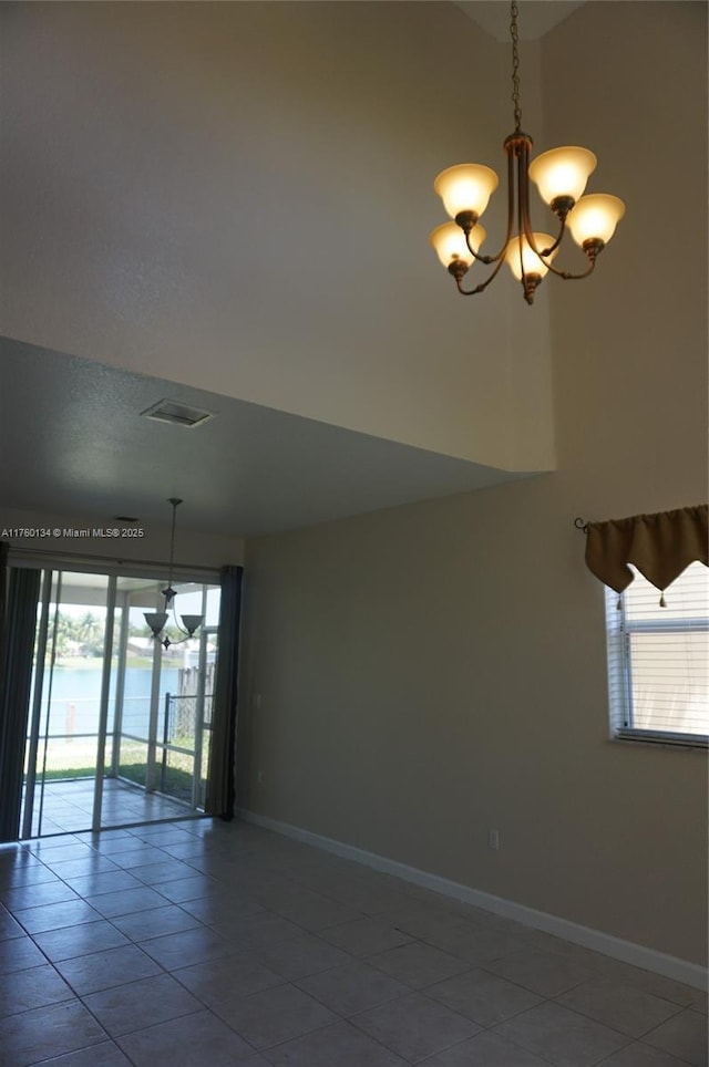 tiled empty room with baseboards, a notable chandelier, and a healthy amount of sunlight