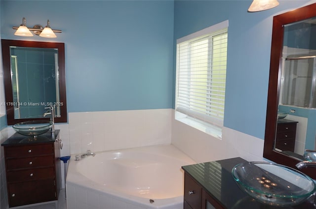 full bathroom featuring a sink, a garden tub, and two vanities