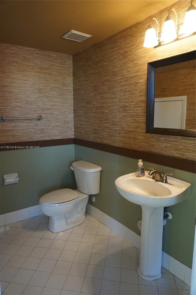 half bathroom with tile patterned flooring, visible vents, toilet, and baseboards