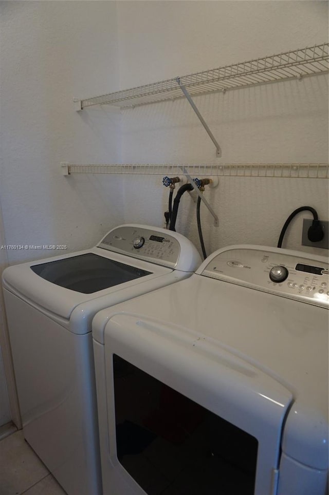 washroom featuring tile patterned floors, laundry area, and washer and clothes dryer