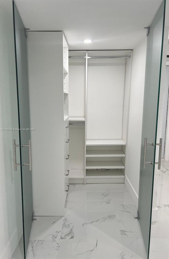 walk in closet featuring marble finish floor