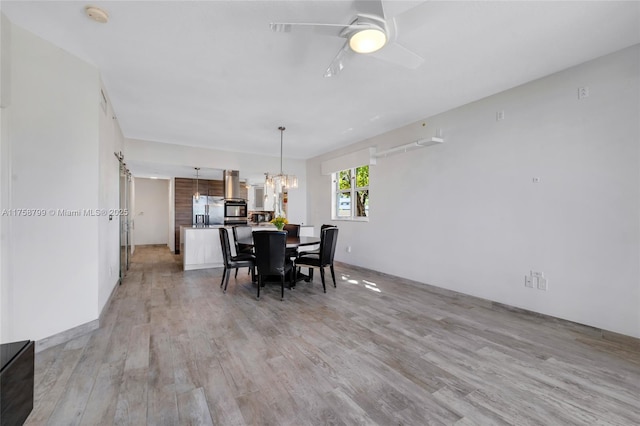 dining space with light wood-style flooring and ceiling fan with notable chandelier