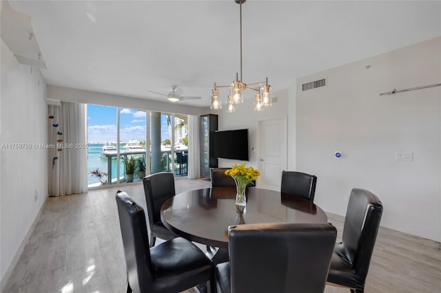 dining area with light wood finished floors, visible vents, and ceiling fan with notable chandelier