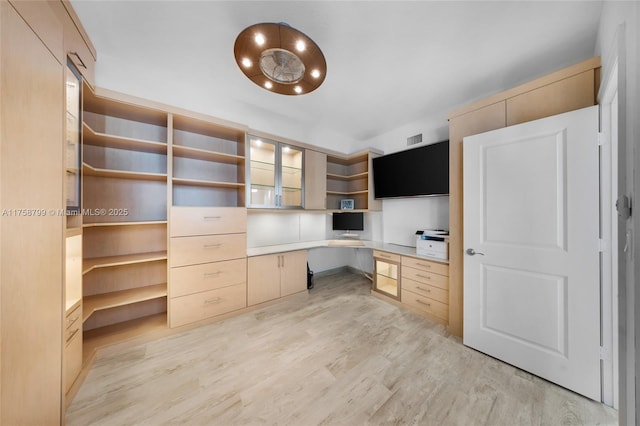 unfurnished office featuring light wood-type flooring, visible vents, and built in study area