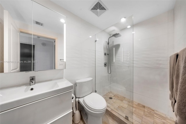 full bath featuring visible vents, toilet, a walk in shower, and tile walls