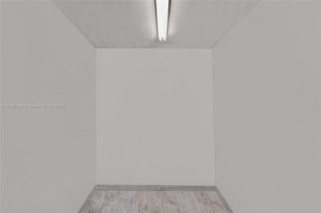 empty room with baseboards and light wood-type flooring