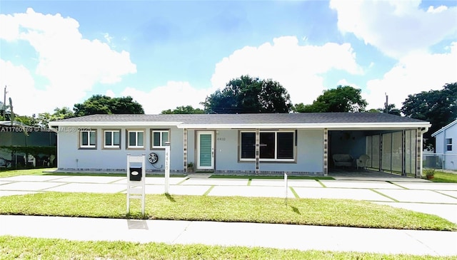 view of front of house featuring stucco siding, a carport, concrete driveway, and a front yard