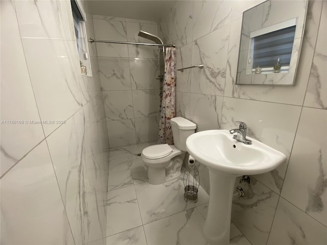 bathroom featuring toilet, marble finish floor, and tiled shower