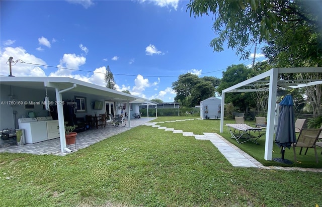 view of yard featuring an outbuilding, washing machine and dryer, a storage unit, and a patio