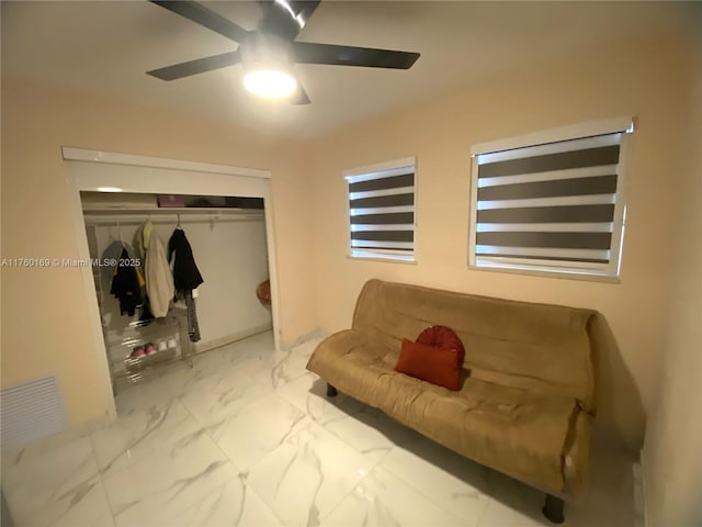 living area with a ceiling fan and marble finish floor